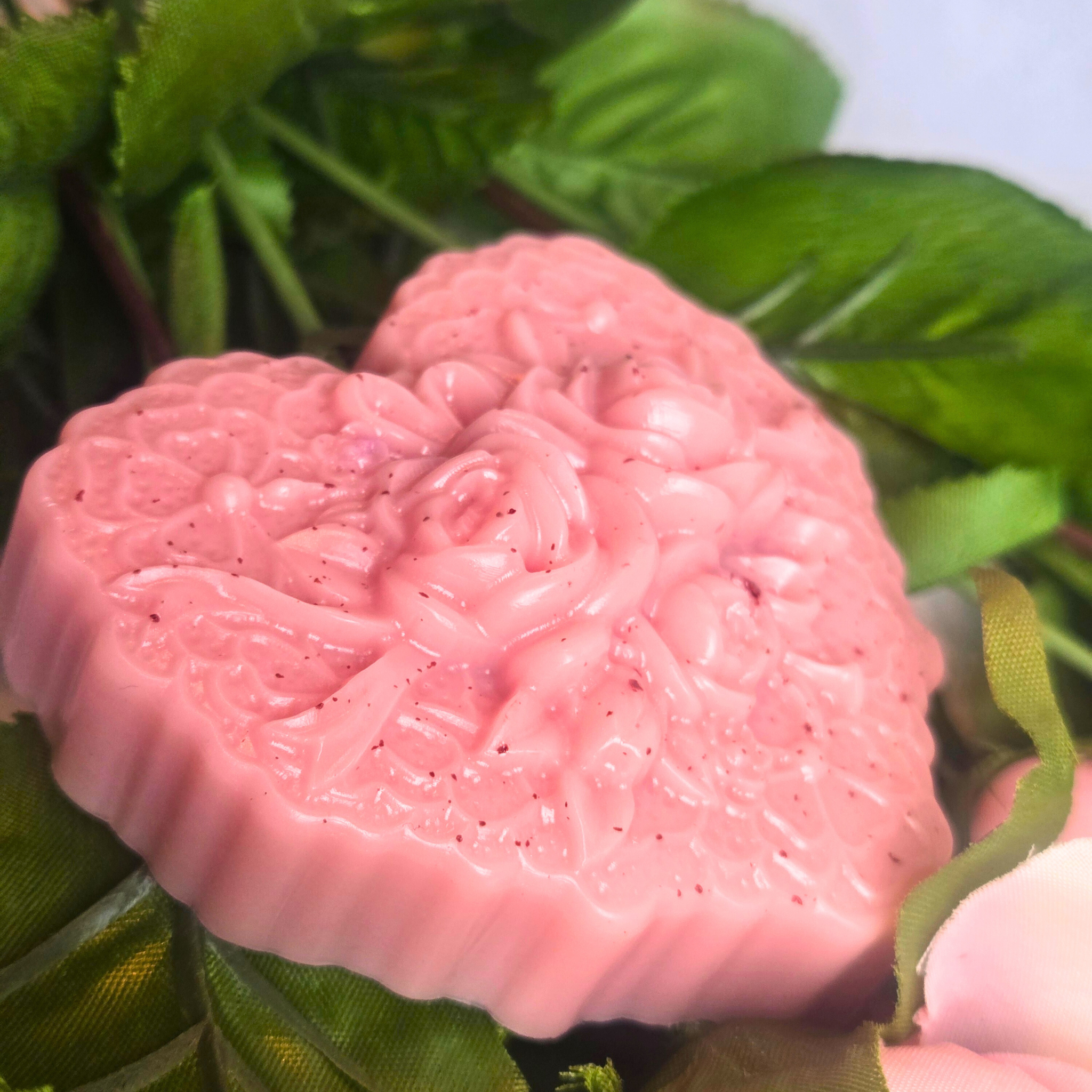 Heart-shaped handcrafted soap bar with creamy texture and Love Spell scent, side view.