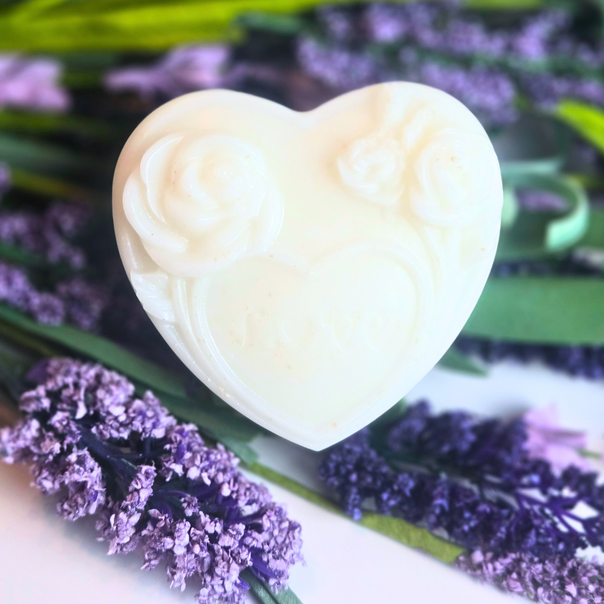 Heart-shaped soap favor with lavender fragrance with purple flowers in the background, front view.