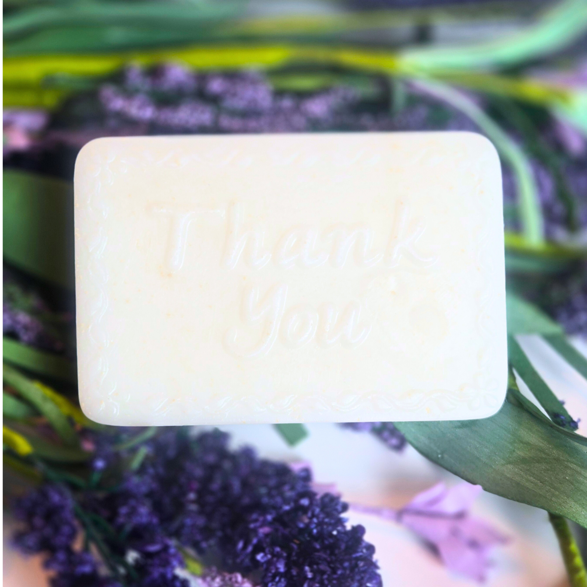 Handcrafted lavender and kaolin clay soap bar stating "Thank You," wrapped as a wedding guest favor, front view.