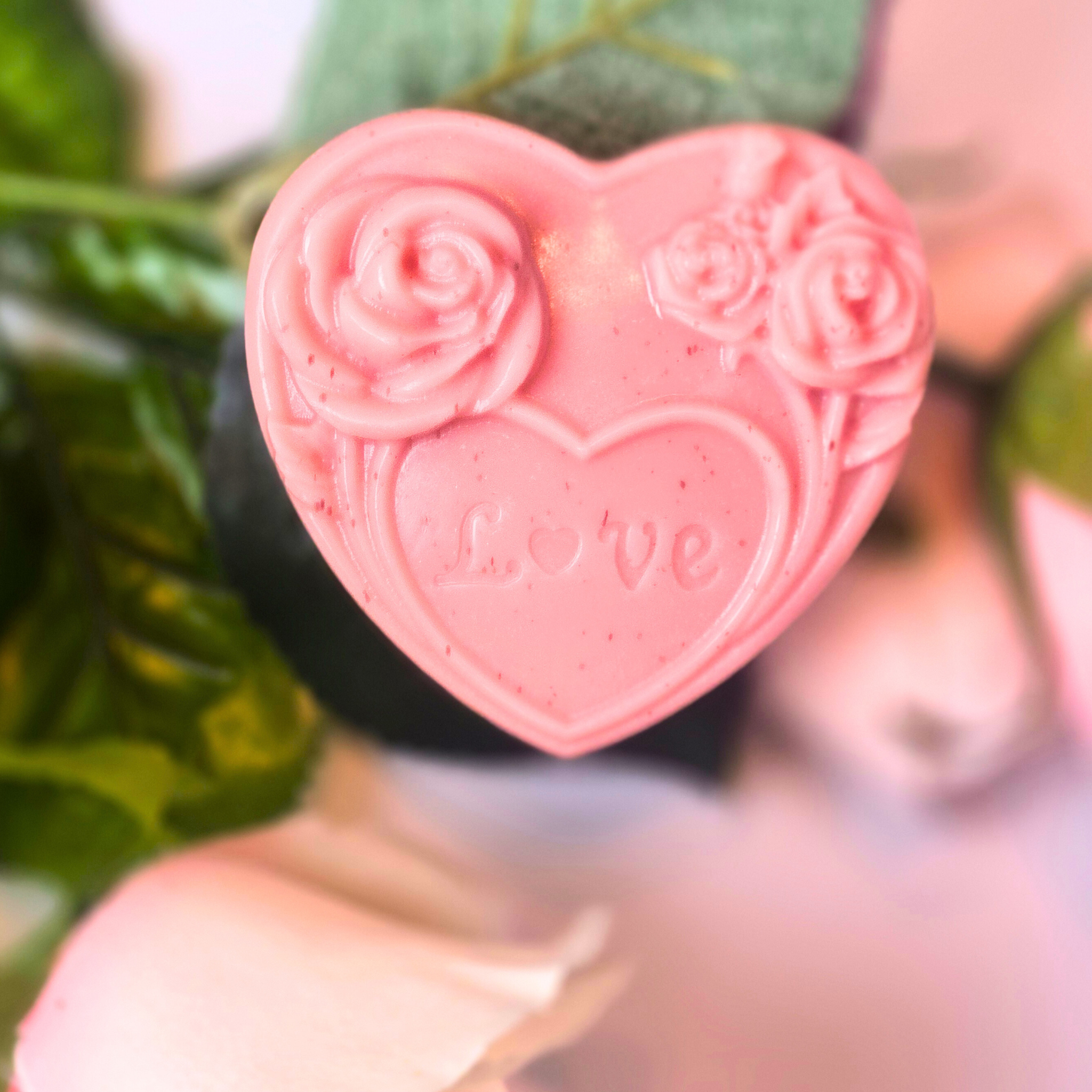 Close-up of rose kaolin clay goat milk soap bars shaped like hearts, front view.