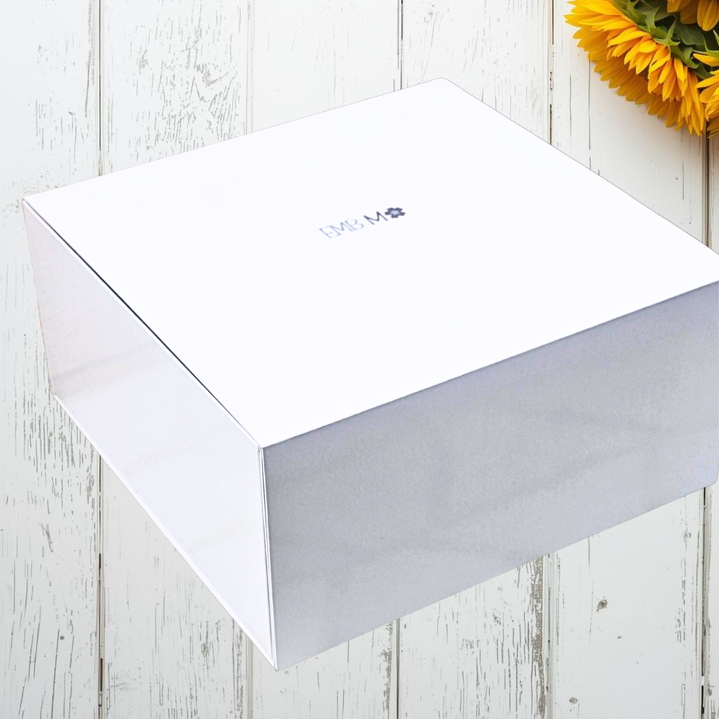 White rectangular box with a brand logo on a wooden surface with sunflowers.