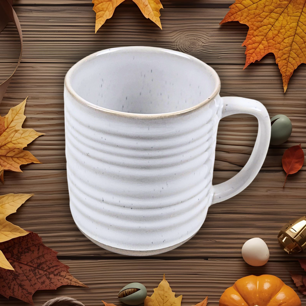 Neutral-colored ceramic mug on a wooden surface with autumn leaves and pumpkins.