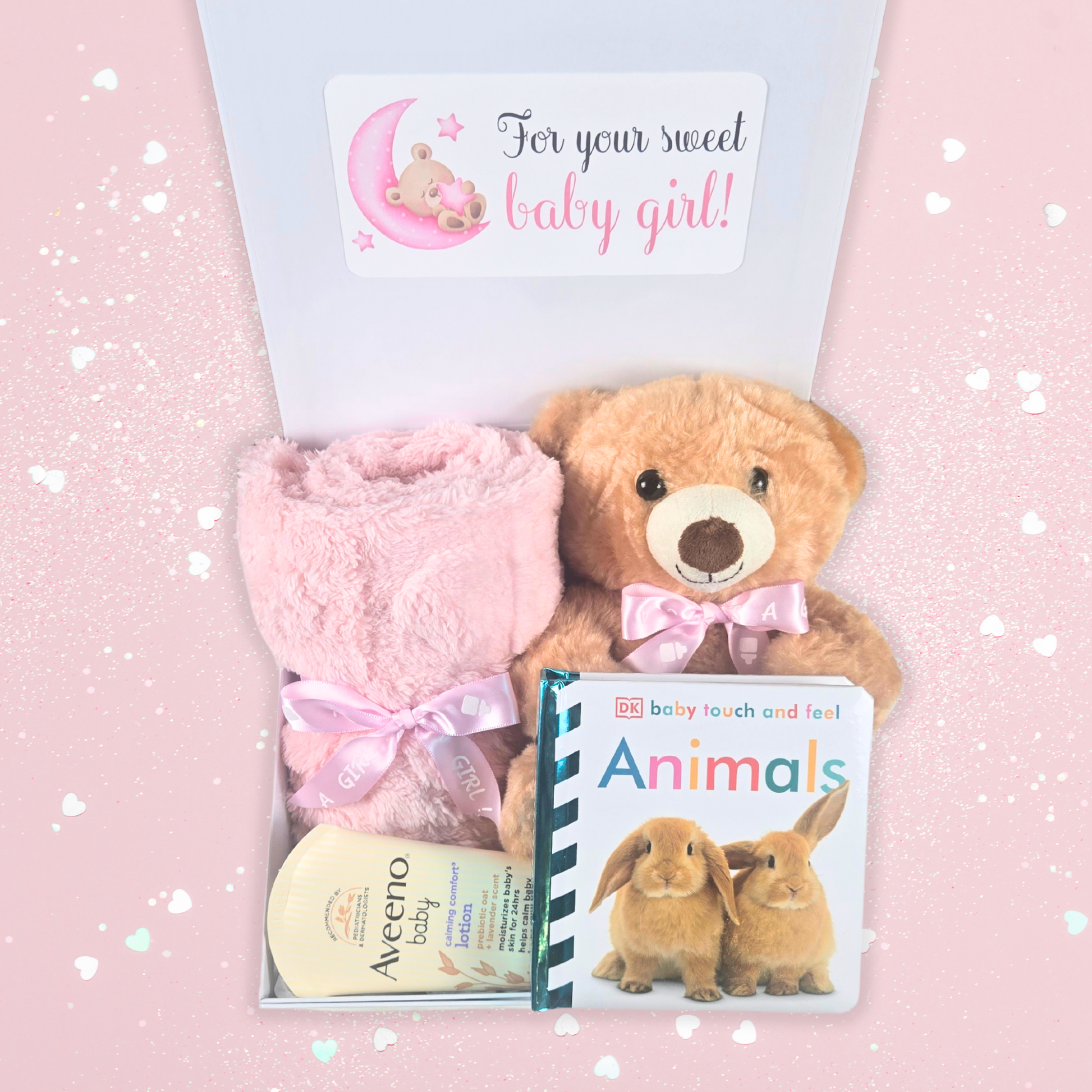 Baby shower gift box for girl including pink baby blanket, bear with pink bow, touch-and-feel book and lavender baby lotion.