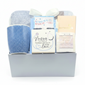A gift set in a white magnetic box featuring a blue textured mug, a blue blanket tied with a white ribbon, decor that reads 'Nursing is the hardest job you'll ever love,' a packaged handcrafted soap, and a cream soap bar.