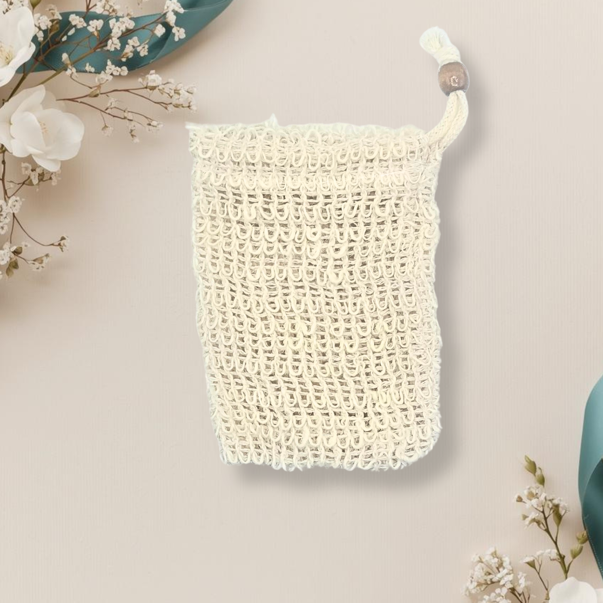 Beige woven soap bag with floral decorations on a beige background