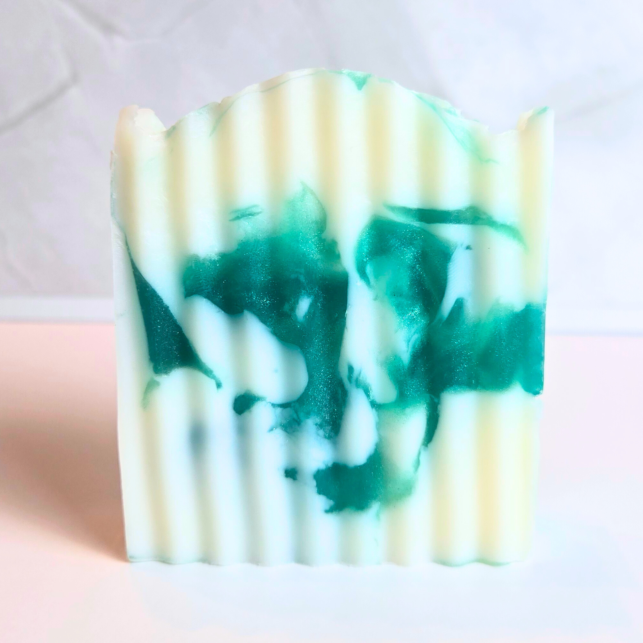 Cooling spearmint artisan soap with elegant green and white swirls, front view.