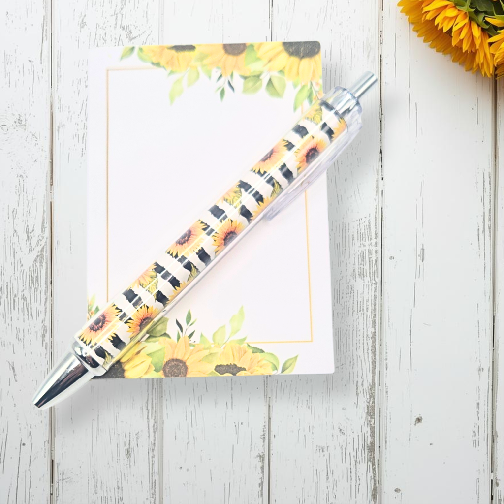 Pen and notebook with sunflower design on a wooden surface