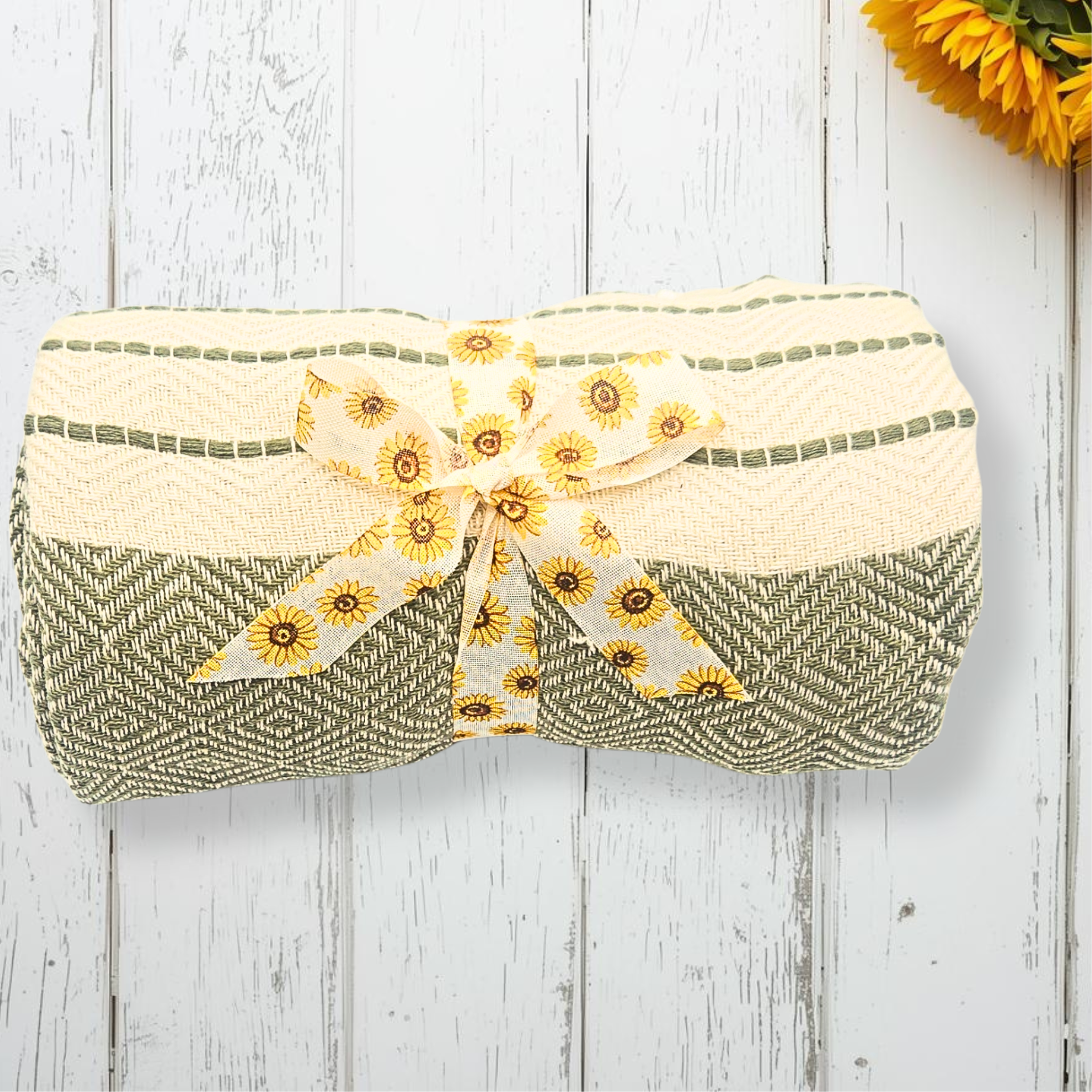 Green and beige throw with a sunflower ribbon on a wooden surface