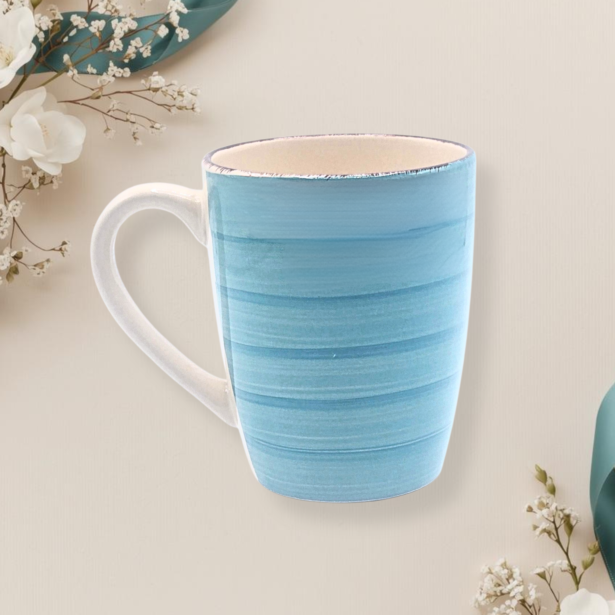 Teal ceramic mug on a light beige surface with white flowers.
