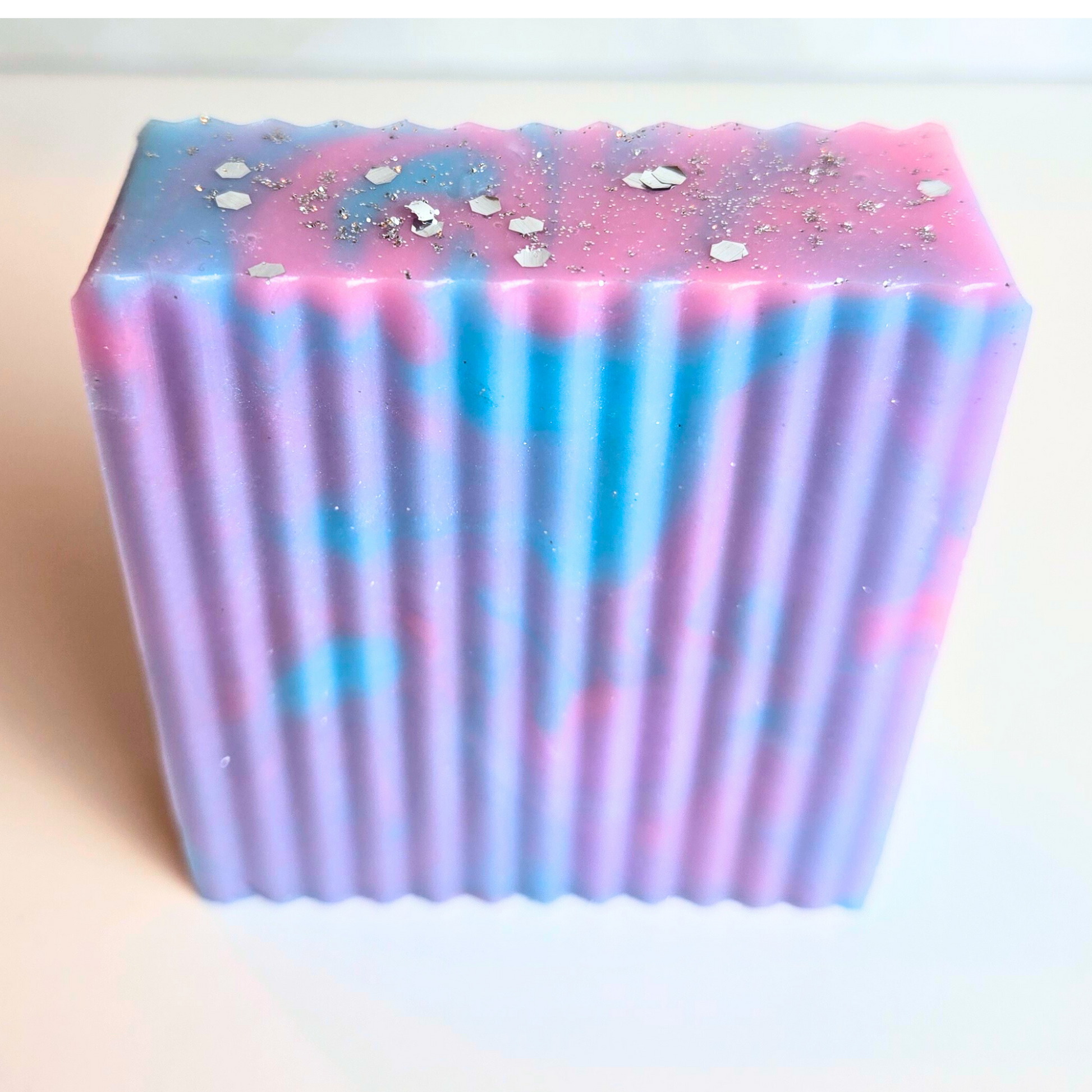 Vibrant sparkly soap bar with handcrafted swirls and glitter, front view.