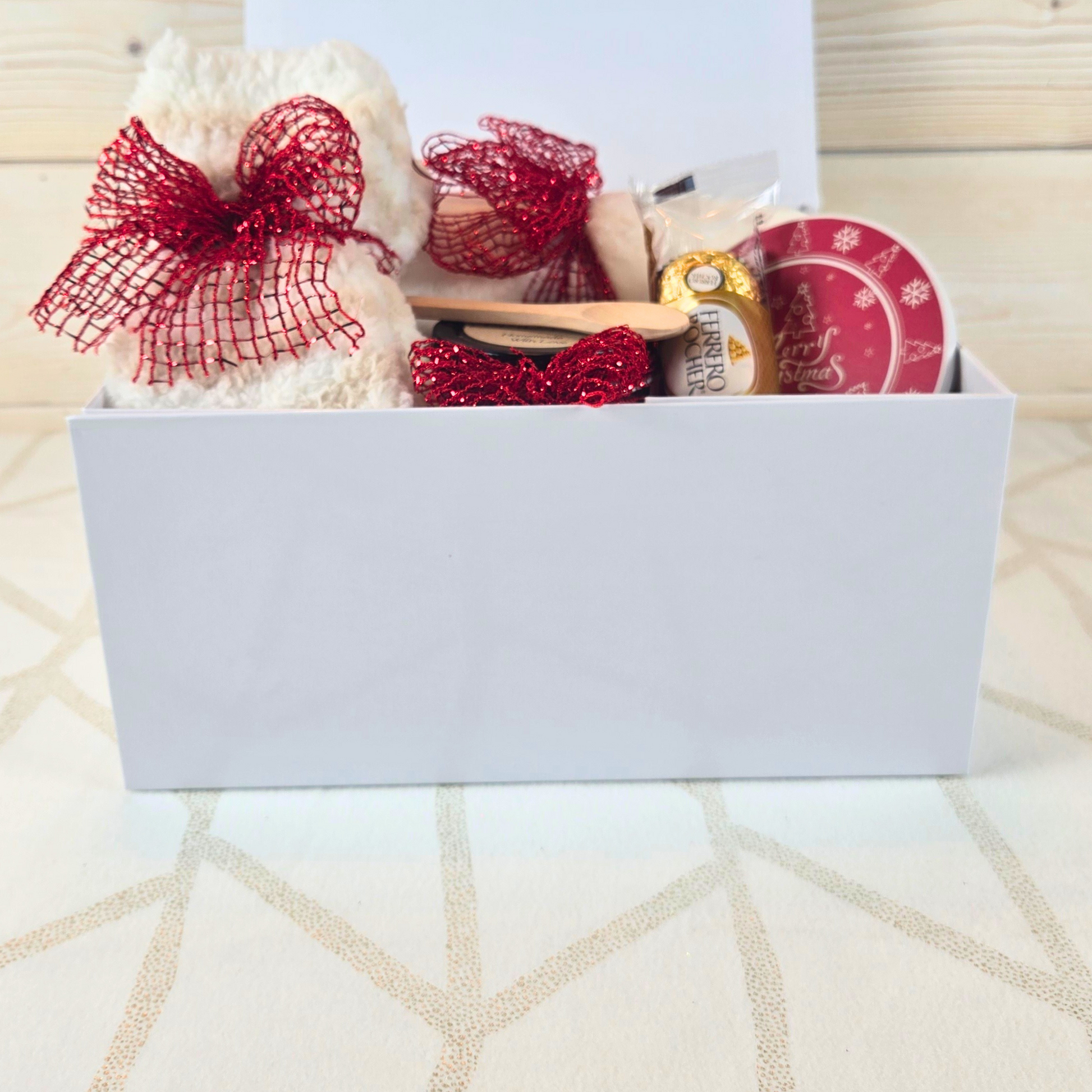 Christmas gift box with magnetic closure lid, featuring a cozy blanket, stylish coaster, sugar scrub, and Ferrero Rocher, perfect for a thoughtful holiday surprise, front view.