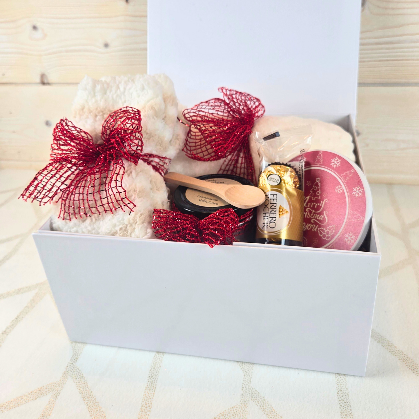 Christmas gift box with magnetic closure lid, featuring a cozy blanket, stylish coaster, sugar scrub, and Ferrero Rocher, perfect for a thoughtful holiday surprise, side view.