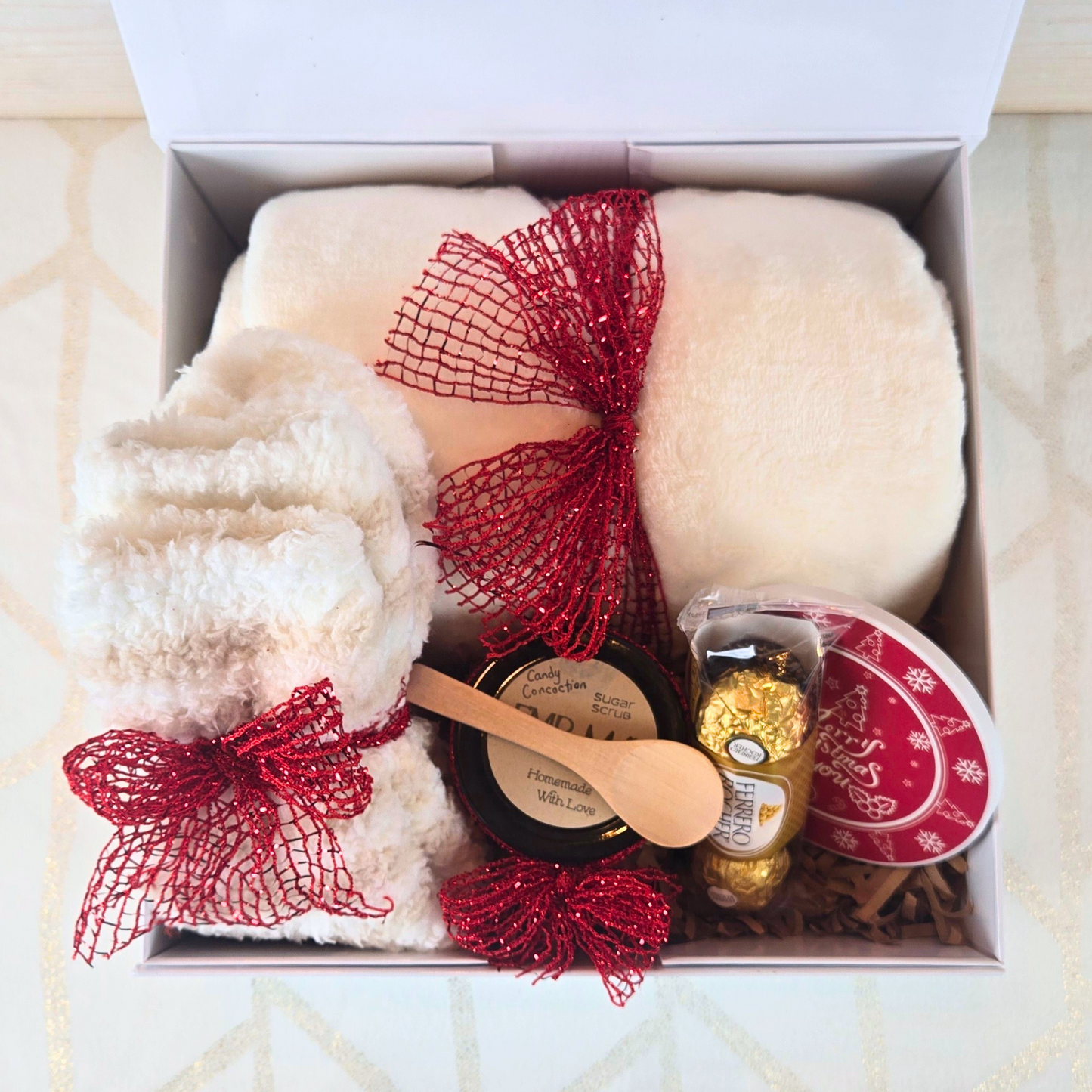 Christmas gift box with magnetic closure lid, featuring a cozy blanket, stylish coaster, sugar scrub, and Ferrero Rocher, perfect for a thoughtful holiday surprise, top view.