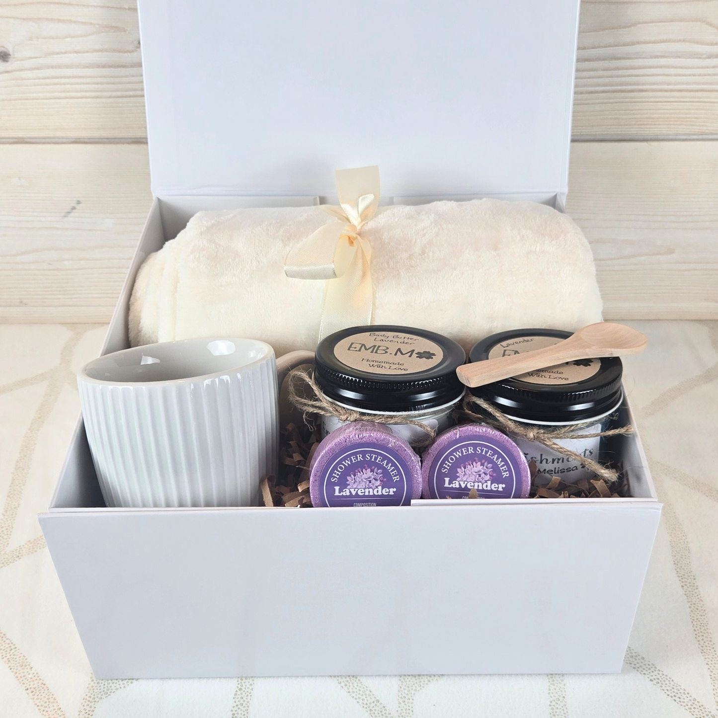 Ultimate pamper gift box for her. Includes a cozy blanket, luxurious body butter, invigorating sugar scrub, stylish mug, and refreshing shower steamers.