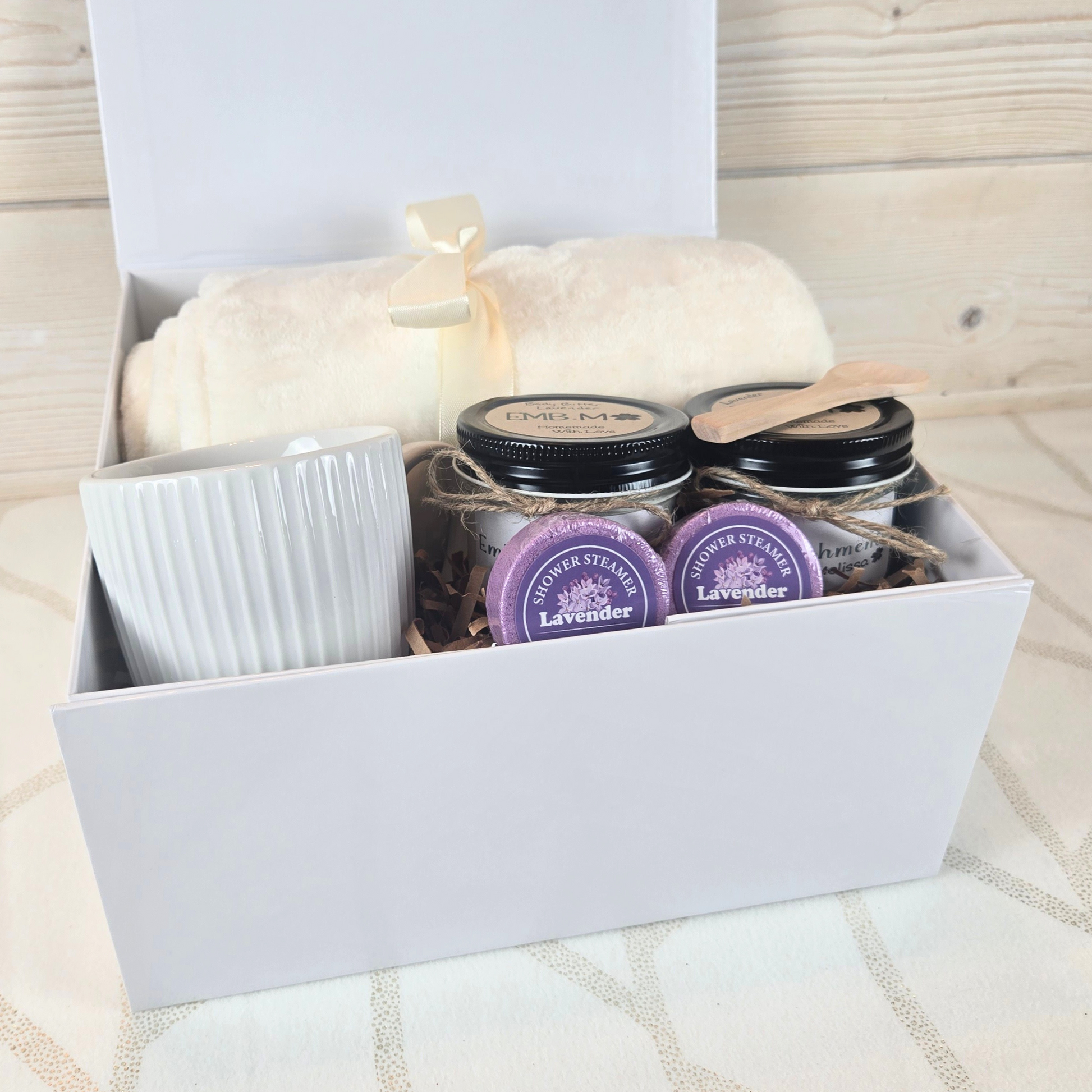 Ultimate pamper gift box for her. Includes a cozy blanket, luxurious body butter, invigorating sugar scrub, stylish mug, and refreshing shower steamers.