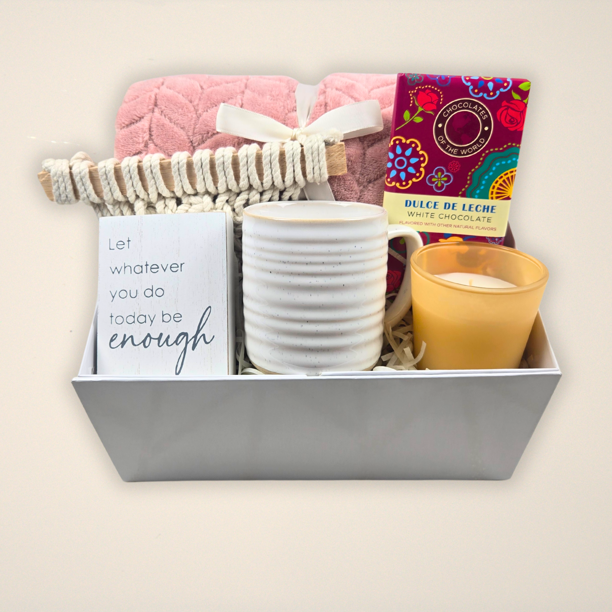 Encouragement gift for her including pink throw, wall decor, mug, vanilla-scented candle and dulce de leche white chocolate bar.