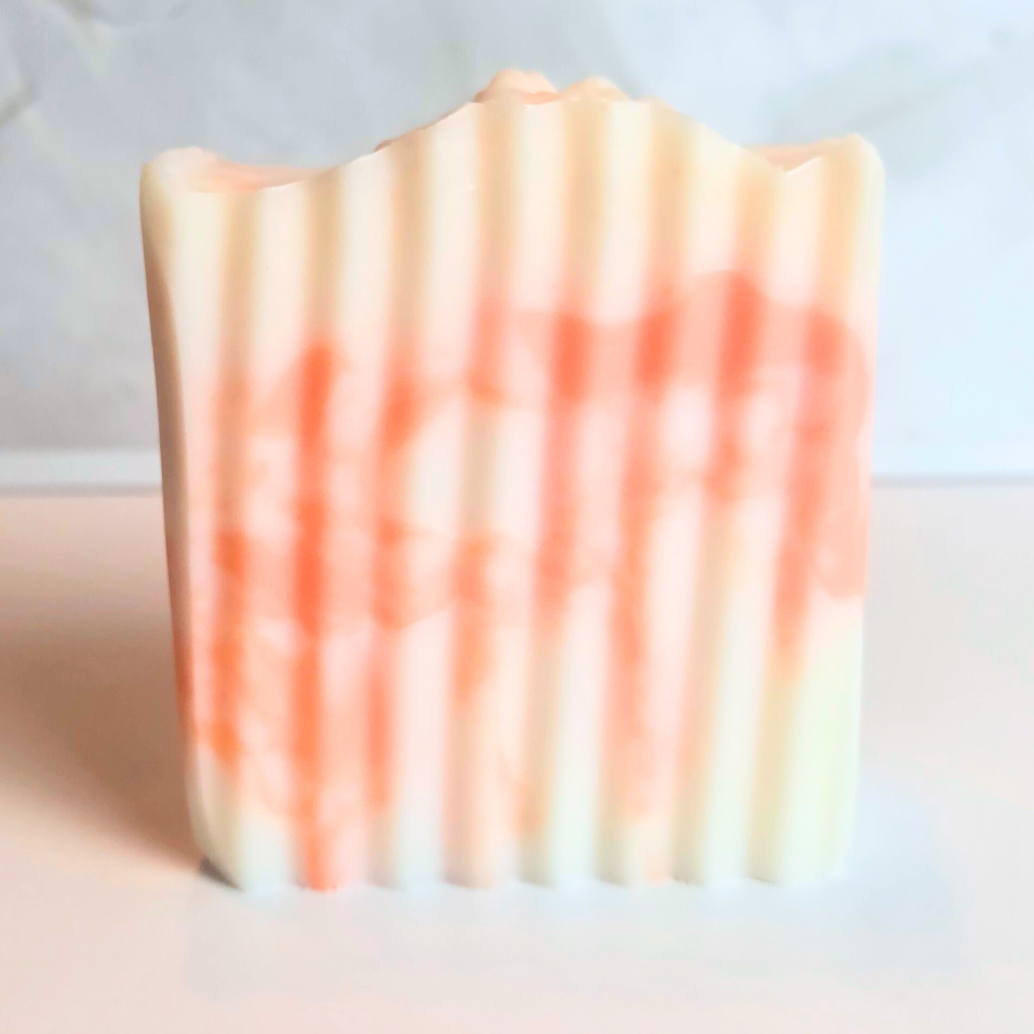 Peach mango-scented artisan soap bar with colorful marbling, front view.
