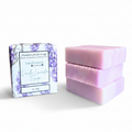 Three lavender-colored handcrafted soap bars next to their decorative package, which features a purple floral pattern and reads 'Vanilla Lavender Escape.'