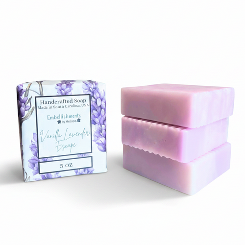 Three lavender-colored handcrafted soap bars next to their decorative package, which features a purple floral pattern and reads 'Vanilla Lavender Escape.'