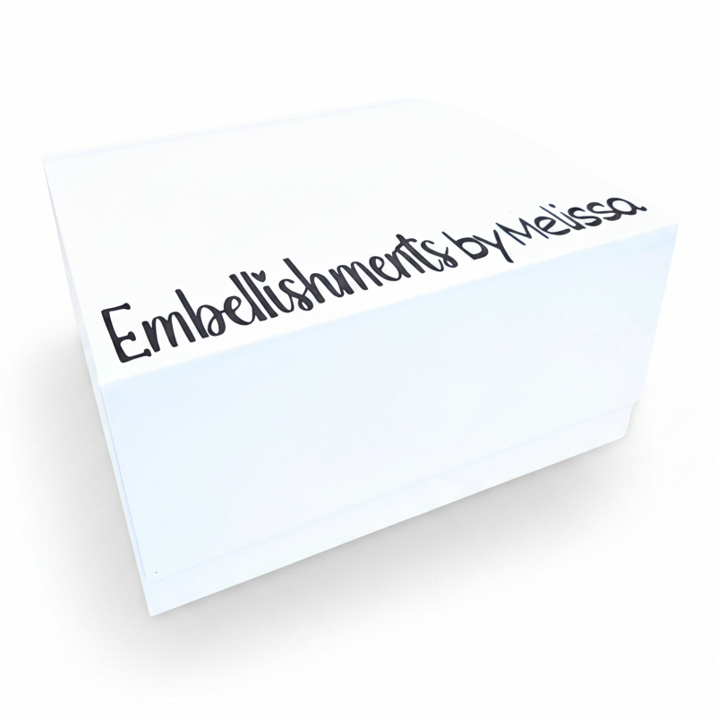A white square box with the text 'Embellishments by Melissa' printed in dark brown script on the top, shown on a clean white background.