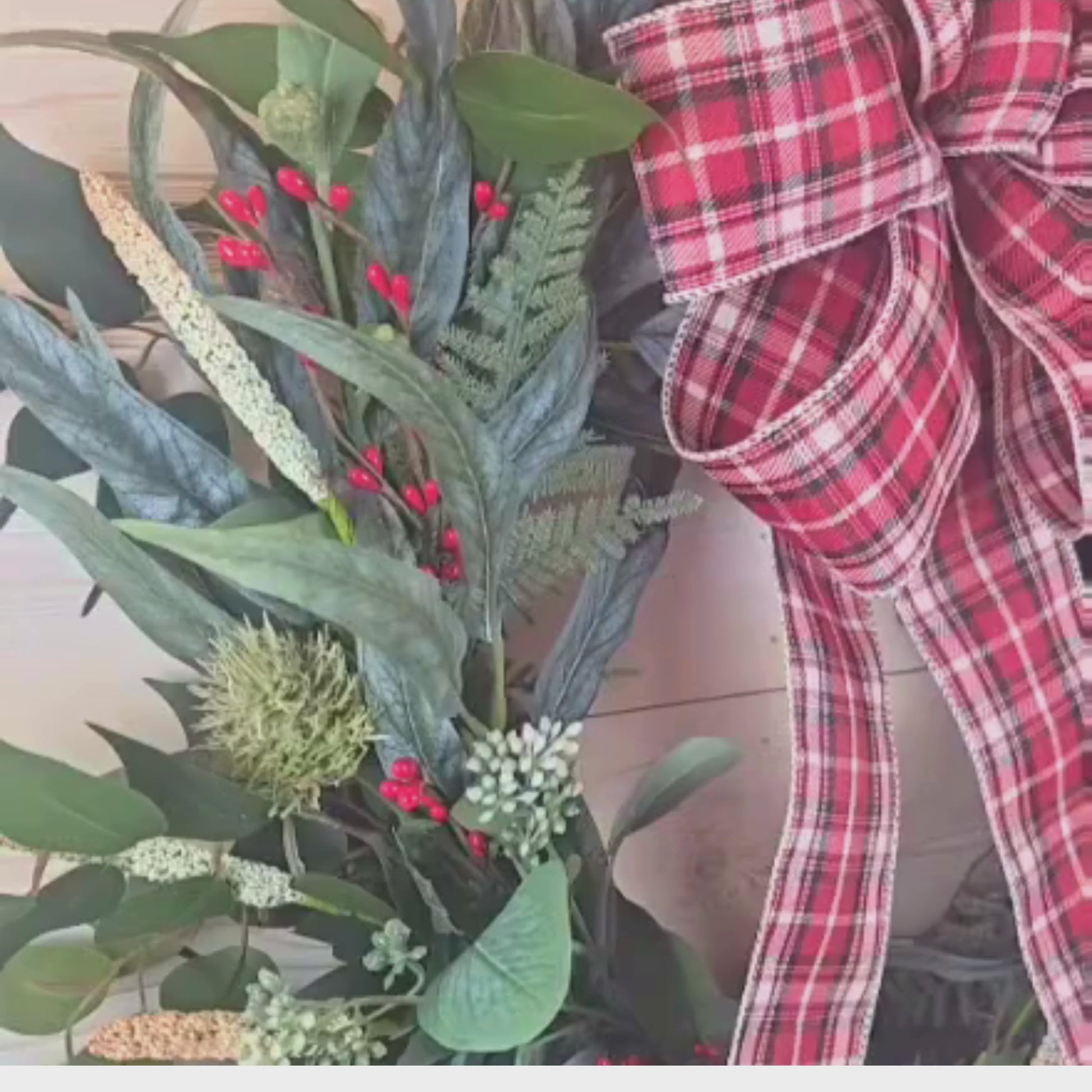 Christmas wreath with red berries and buffalo plaid bow.